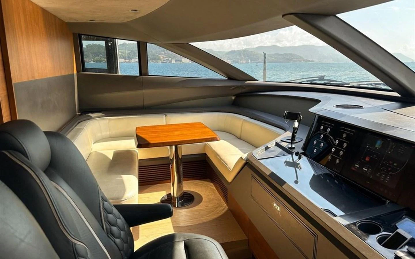 The helm area features a comfortable seating arrangement with a wooden table and modern navigation controls. aboard PRINCESS Y88 Yacht for Sale