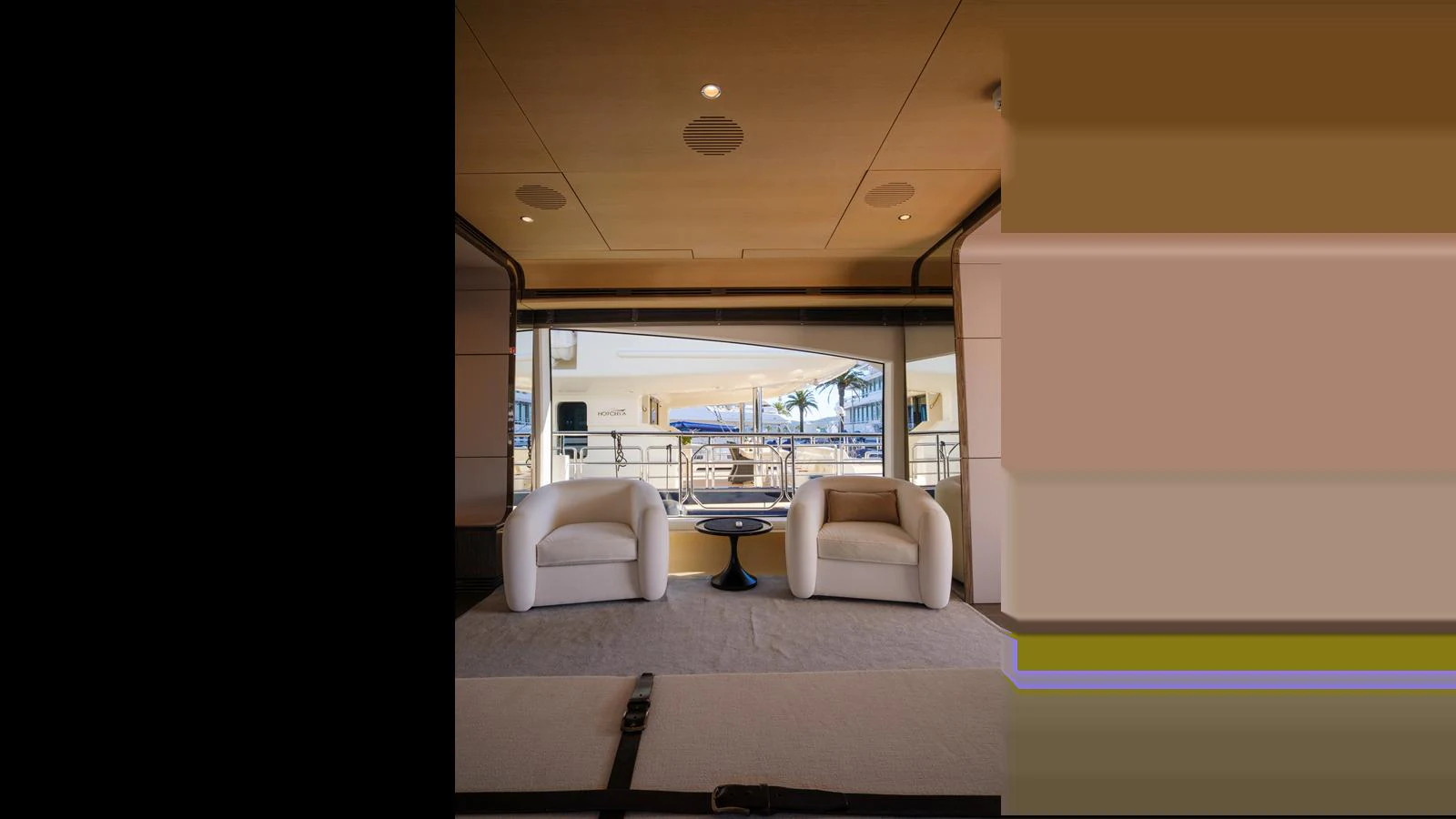 The yacht's interior features a cozy seating area with two armchairs and a small table, offering a view of the exterior deck. aboard 98.92' AZIMUT GRANDE Yacht for Sale
