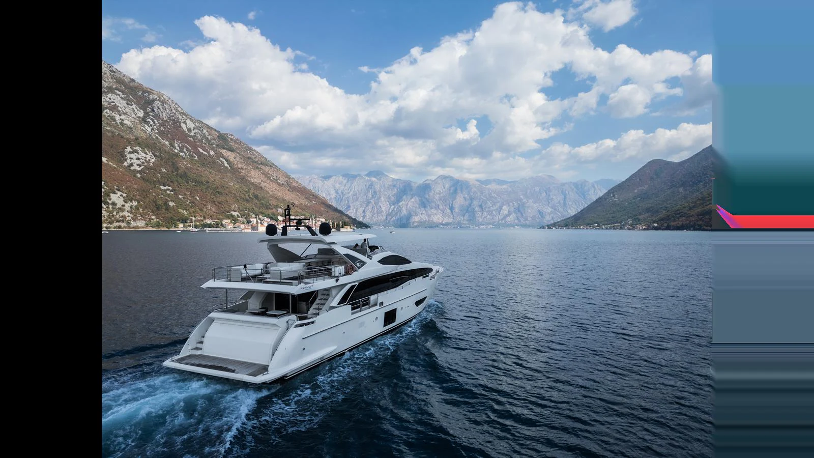 A sleek yacht cruises through a picturesque mountainous landscape under a partly cloudy sky. aboard 98.92' AZIMUT GRANDE Yacht for Sale
