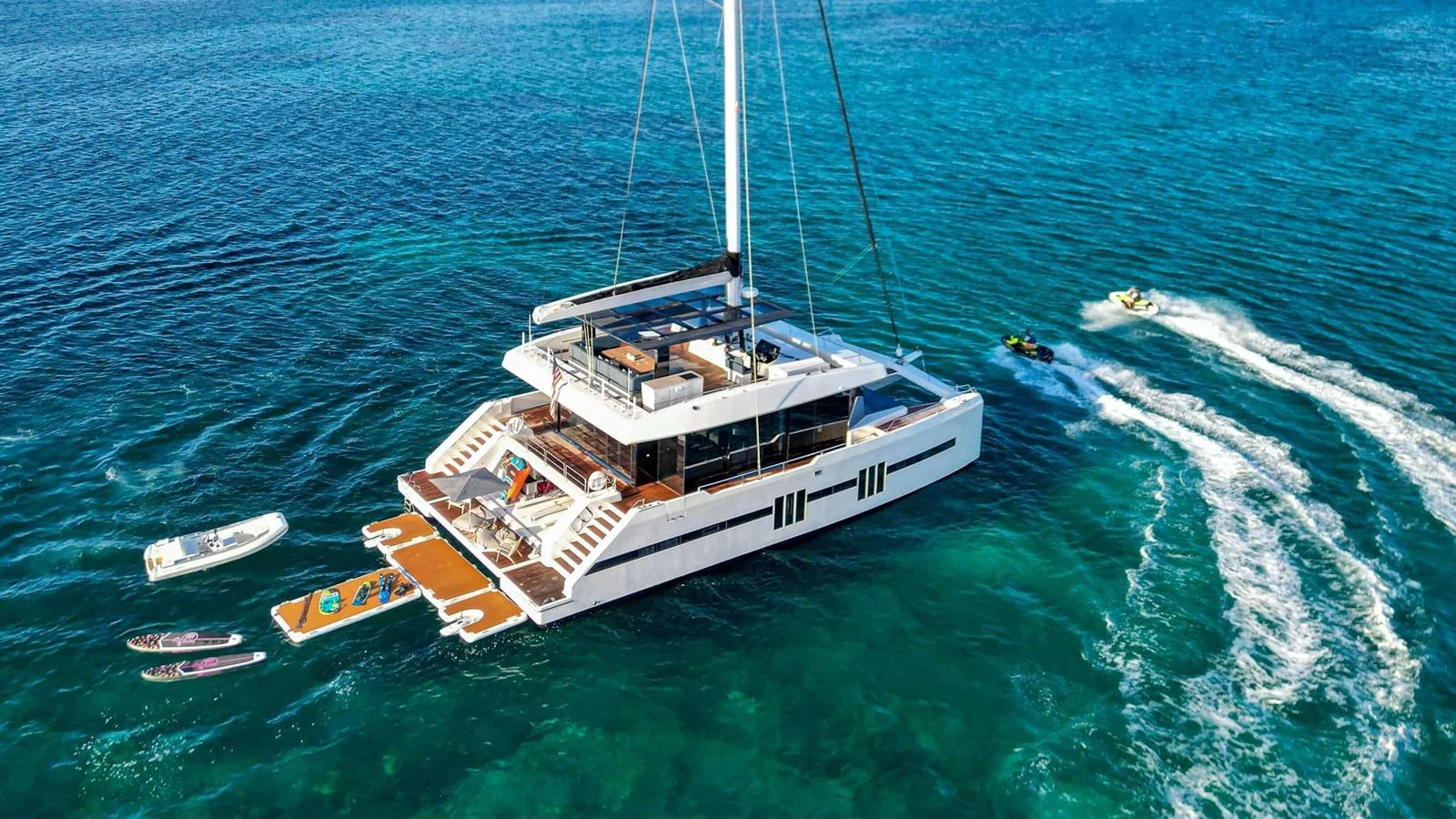 A luxurious yacht is anchored in clear blue waters, showcasing its spacious deck and water toys. aboard MIDORI Yacht for Sale