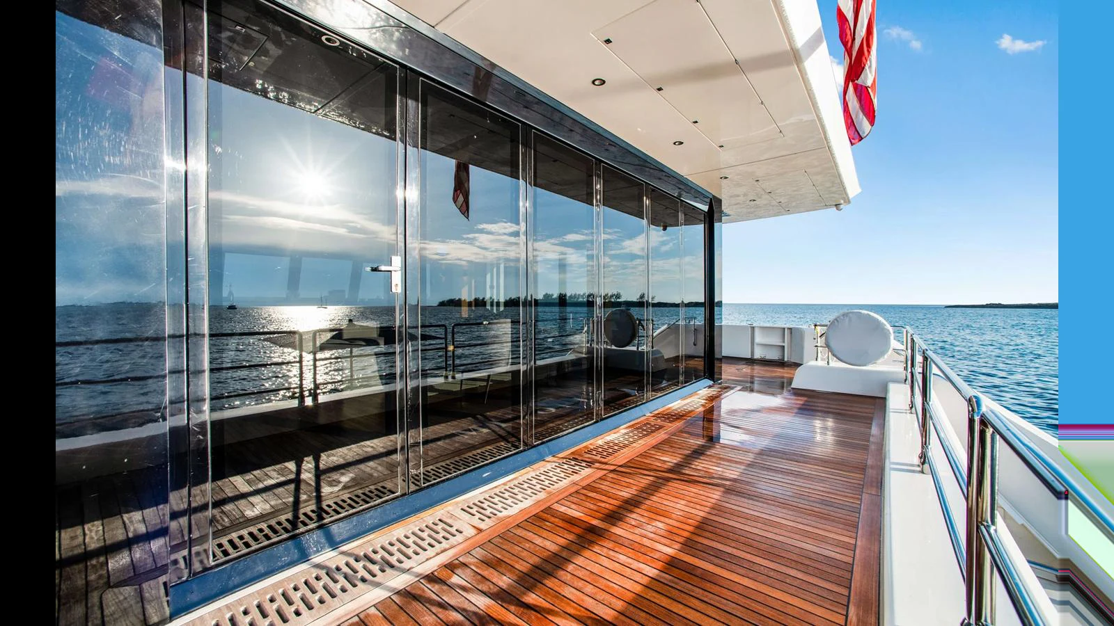 The aft deck features sleek wooden flooring and expansive glass doors, offering stunning ocean views. aboard MIDORI Yacht for Sale