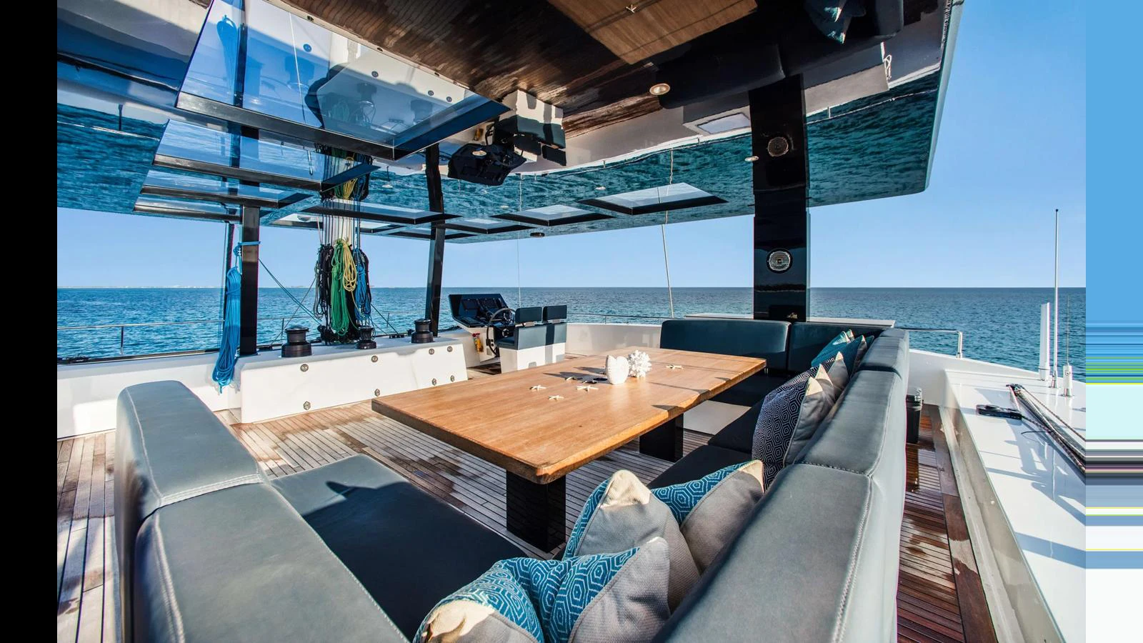 The aft deck features a spacious seating area with a large wooden table, perfect for outdoor dining and relaxation. aboard MIDORI Yacht for Sale