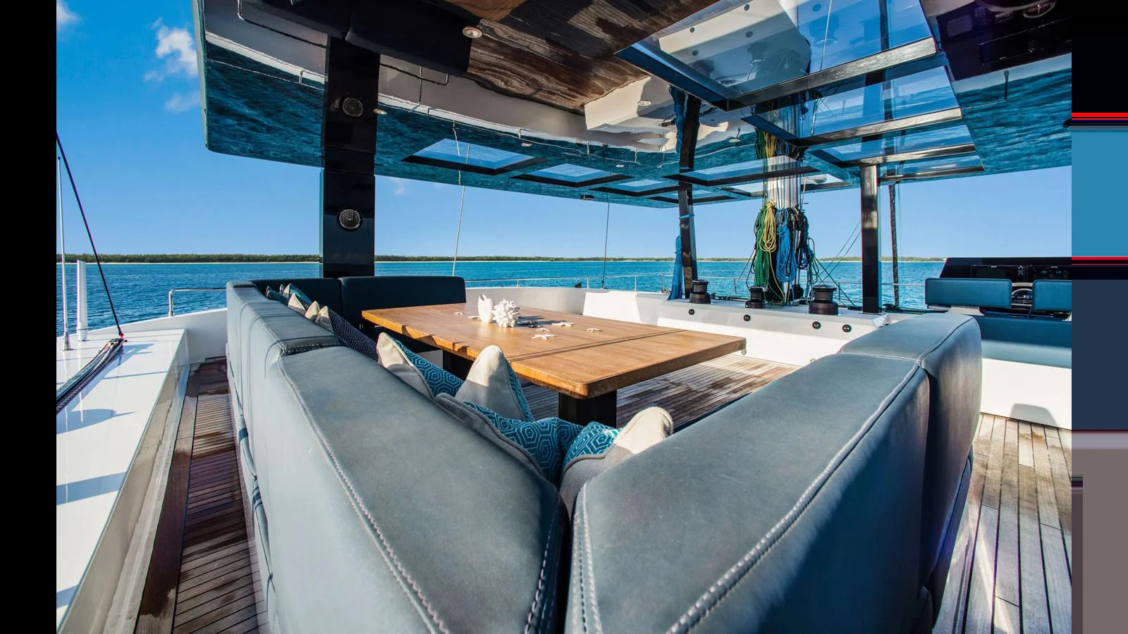 The aft deck features a spacious seating area with a large wooden table, perfect for outdoor dining and relaxation. aboard MIDORI Yacht for Sale