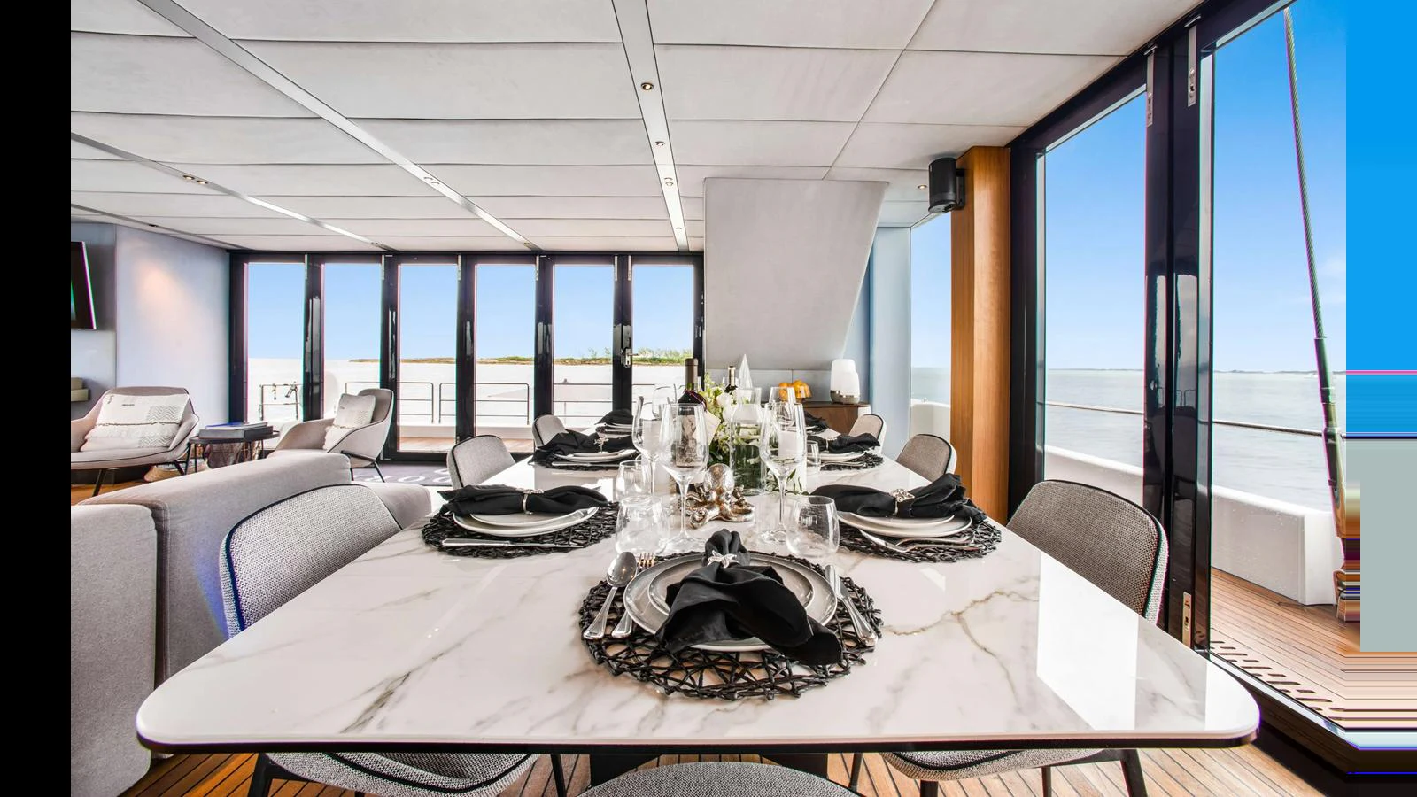 The yacht's dining area features a sleek marble table set with elegant tableware, offering a luxurious dining experience with a view of the sea. aboard MIDORI Yacht for Sale