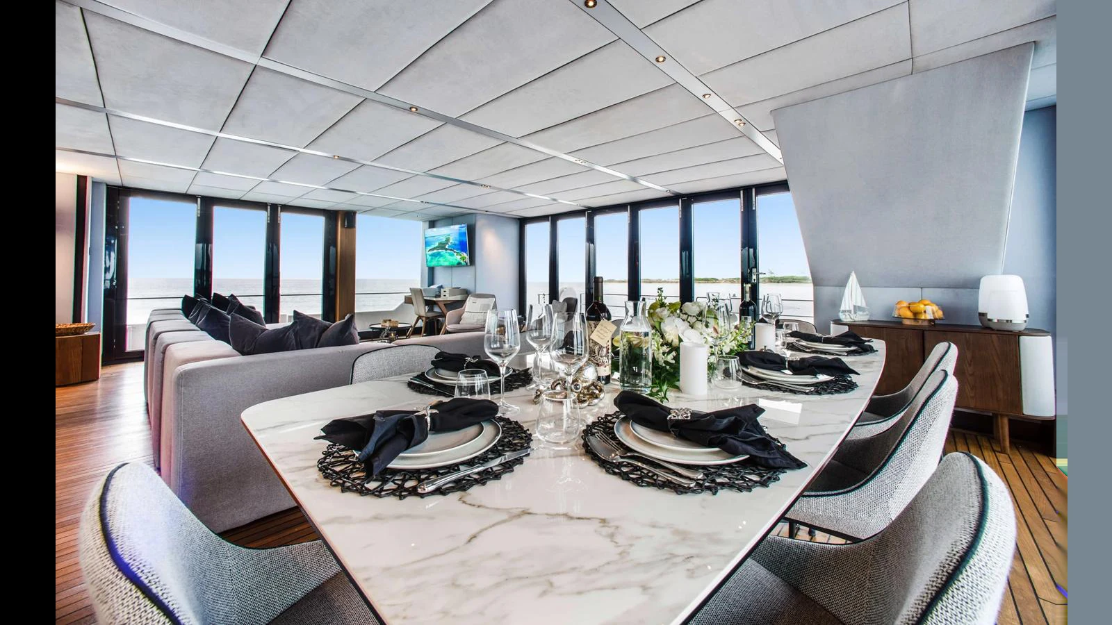 The yacht's dining area features a luxurious marble table set for an elegant meal, with panoramic windows offering stunning ocean views. aboard MIDORI Yacht for Sale