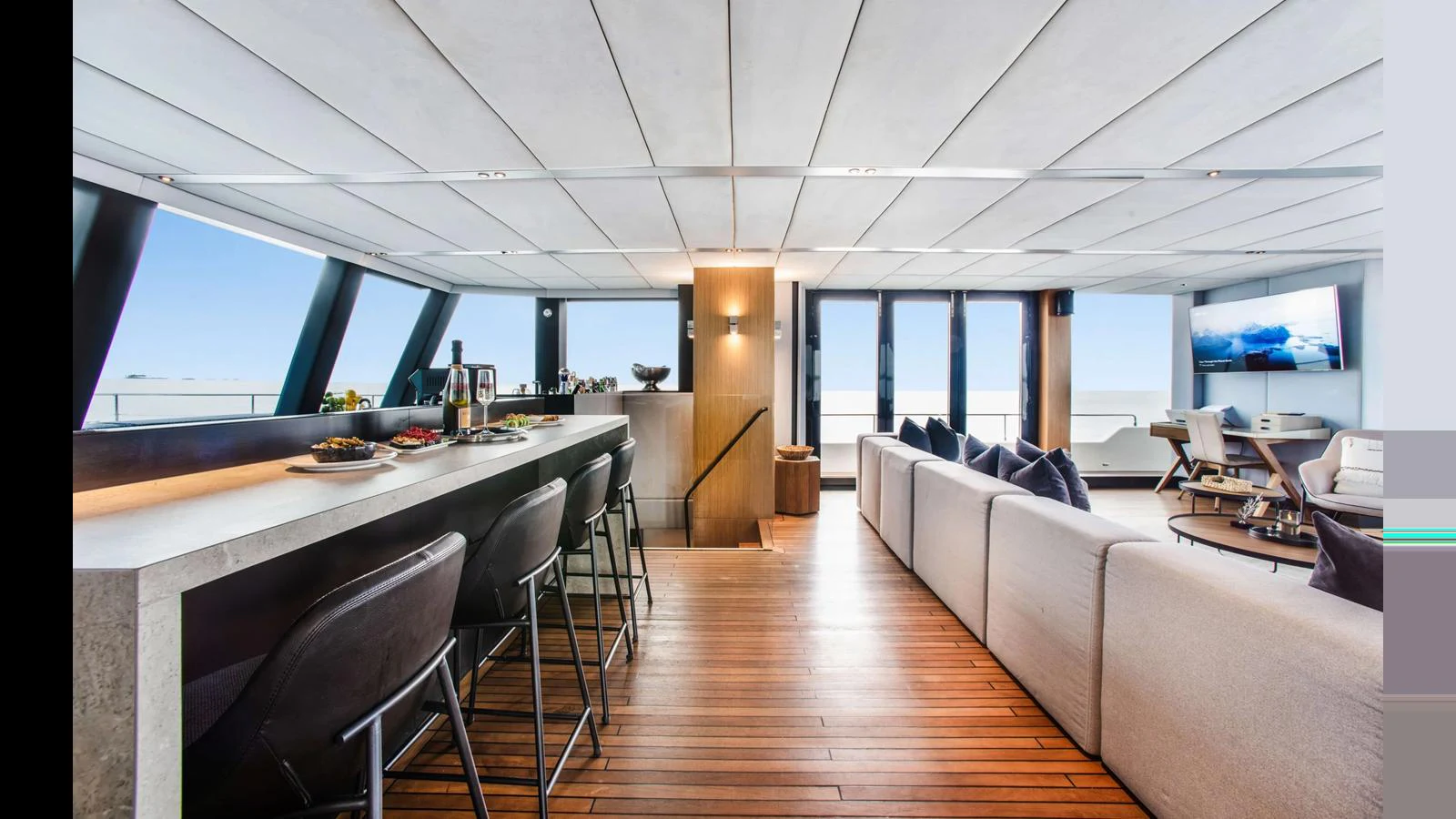 The spacious salon features a modern design with a bar, comfortable seating, and large windows offering stunning views. aboard MIDORI Yacht for Sale