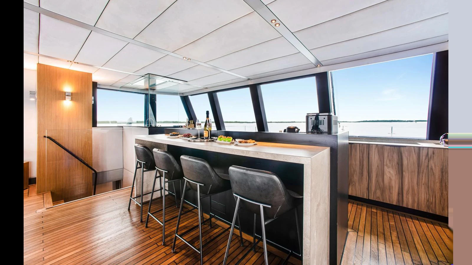 The yacht's interior features a sleek bar area with ample seating and panoramic windows offering stunning views. aboard MIDORI Yacht for Sale