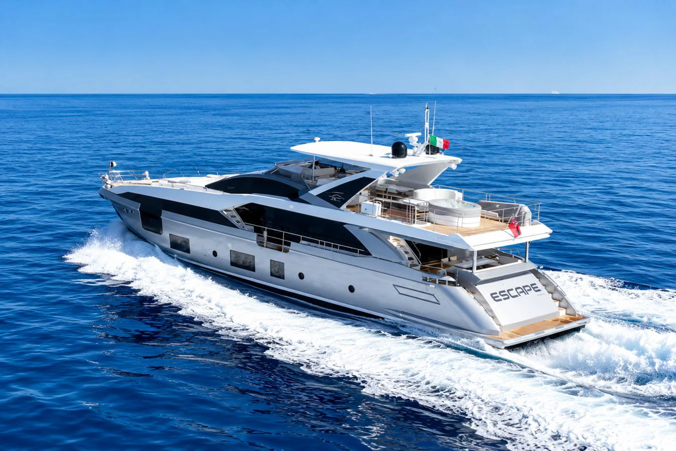 A sleek and modern yacht cruises through the open sea under a clear blue sky. aboard ESCAPE Yacht for Sale