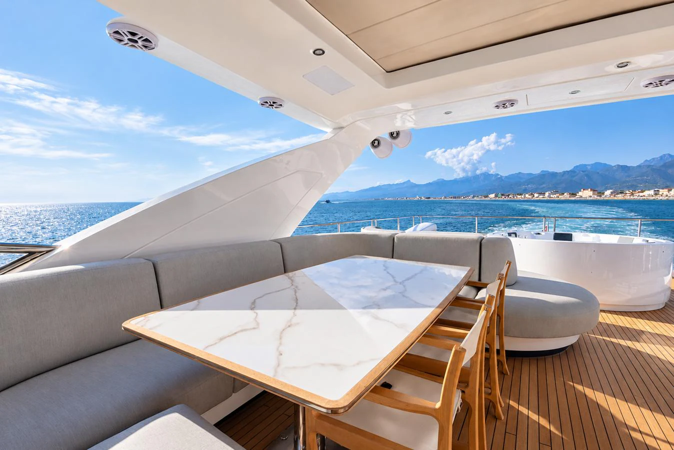 The aft deck features a luxurious dining area with a stunning ocean view. aboard ESCAPE Yacht for Sale