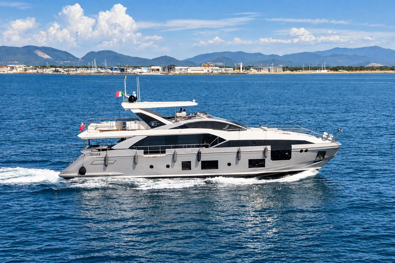 A sleek and modern yacht cruises gracefully on calm blue waters with a scenic coastal backdrop. aboard ESCAPE Yacht for Sale