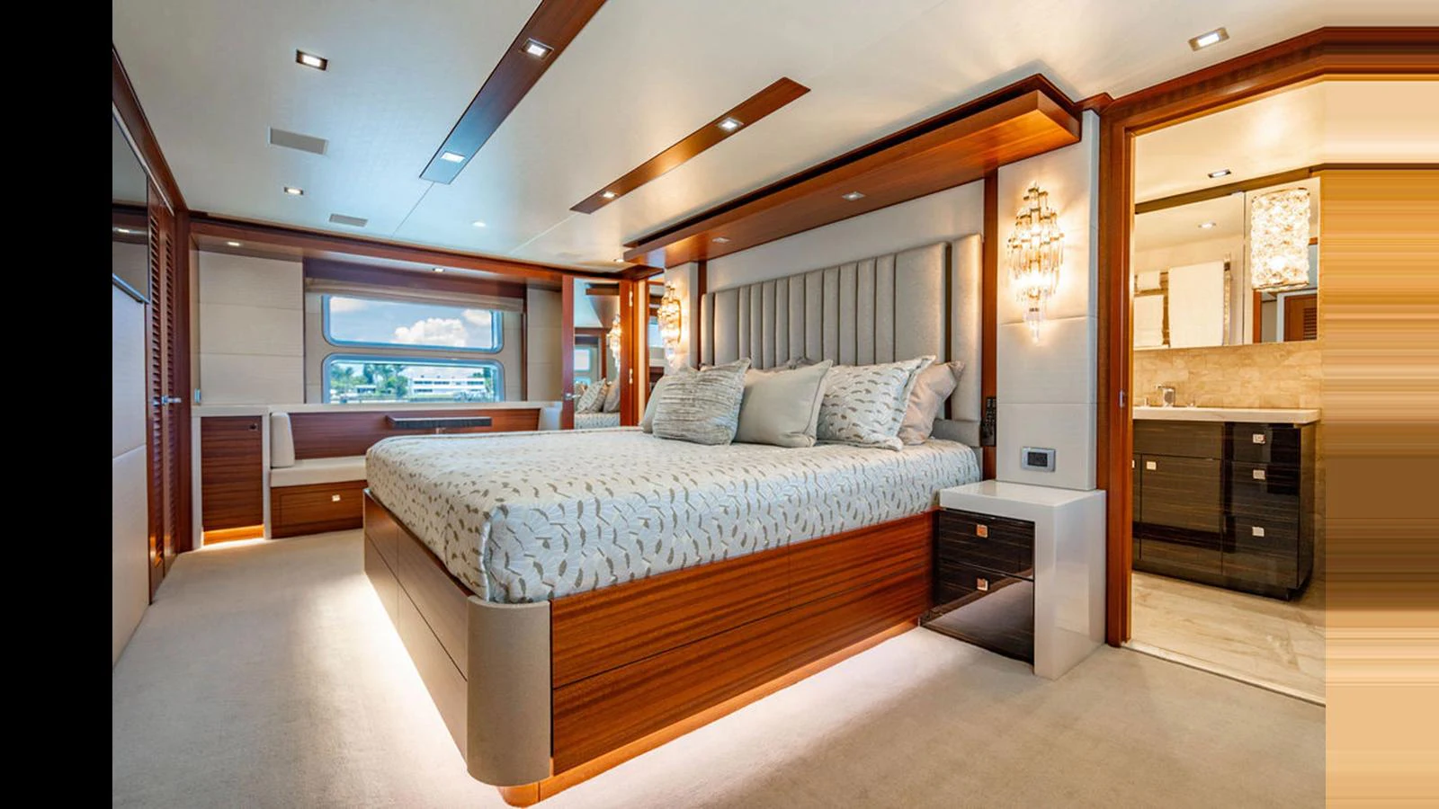 The master stateroom features a luxurious bed with elegant lighting and ample natural light from large windows. aboard TRU LUV Yacht for Sale