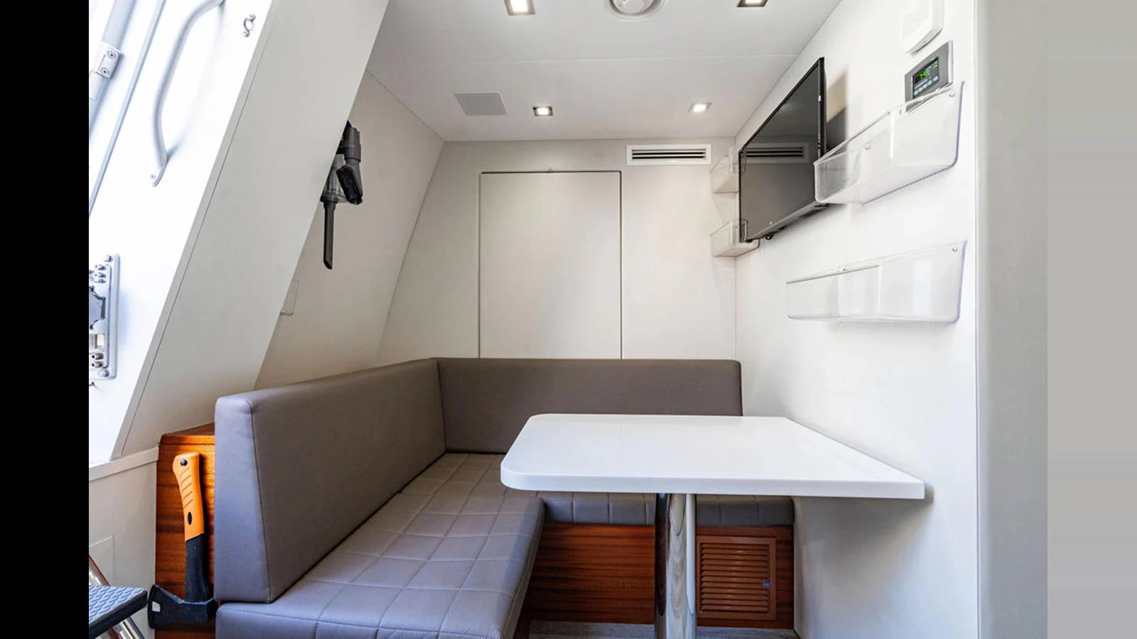 A cozy dining nook with a table and cushioned seating, complemented by a wall-mounted TV and modern lighting. aboard TRU LUV Yacht for Sale
