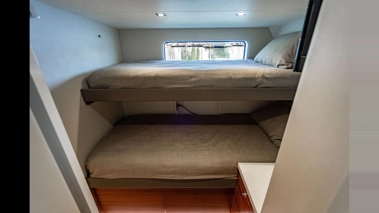 The cozy cabin features bunk beds with soft lighting and a small window for natural light. aboard TRU LUV Yacht for Sale