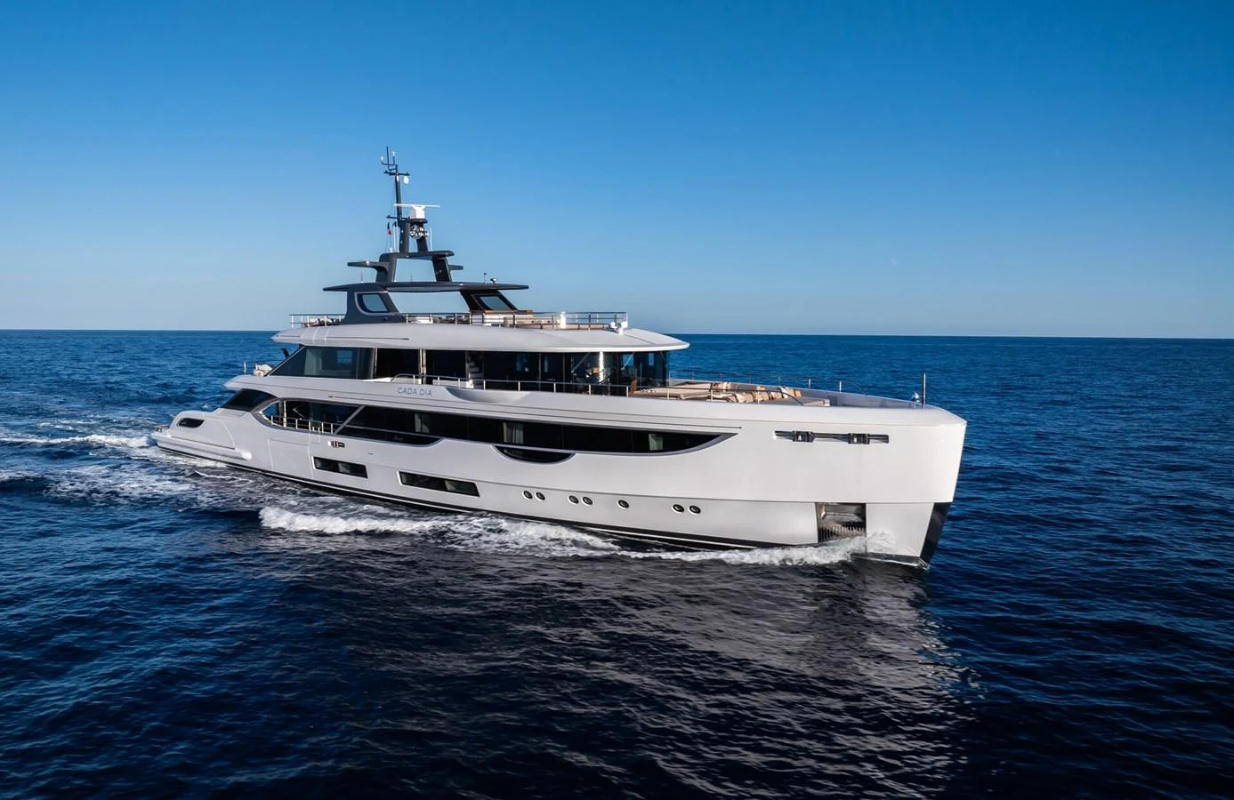 A sleek and modern yacht cruises through the open sea under a clear blue sky. aboard CADA DIA Yacht for Sale