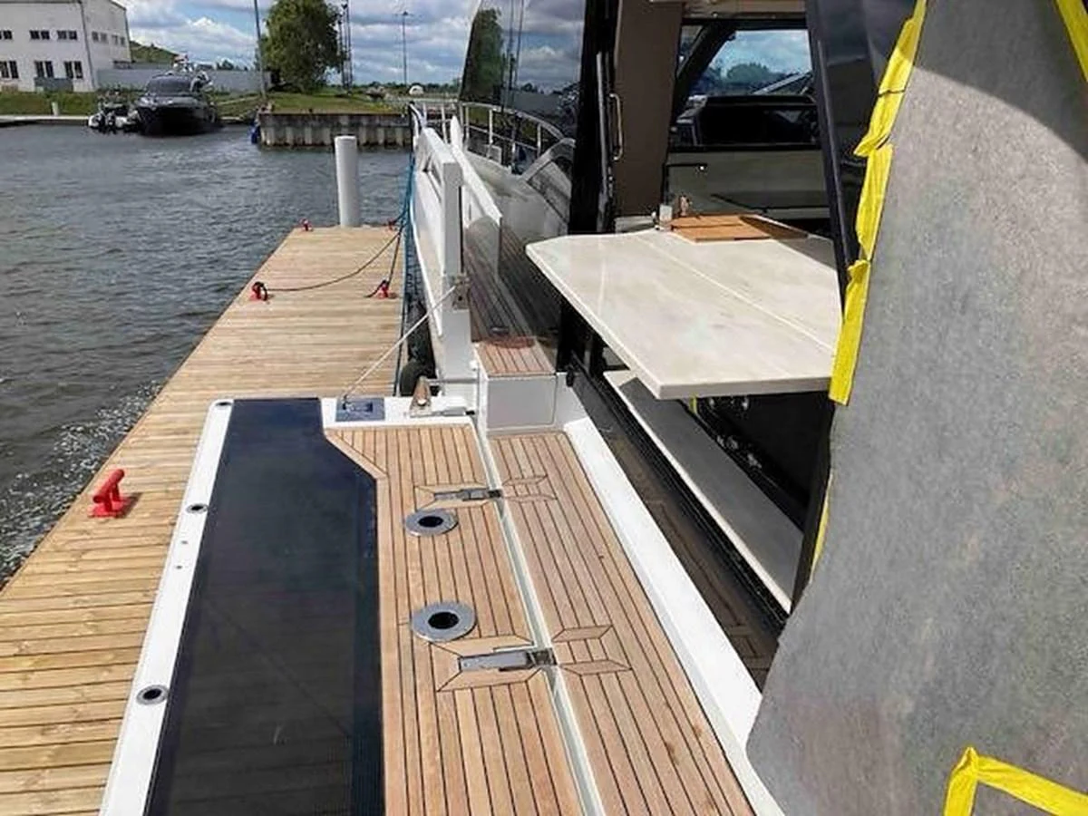 The yacht is docked, showcasing its aft deck with a fold-out table and sleek design. aboard GLN Yacht for Sale