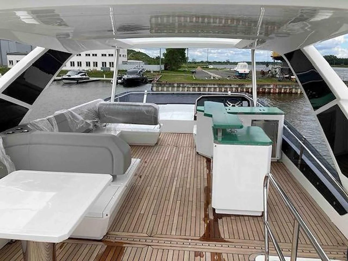 The aft deck features a spacious seating area with a table and a small bar, perfect for outdoor relaxation and entertainment. aboard GLN Yacht for Sale