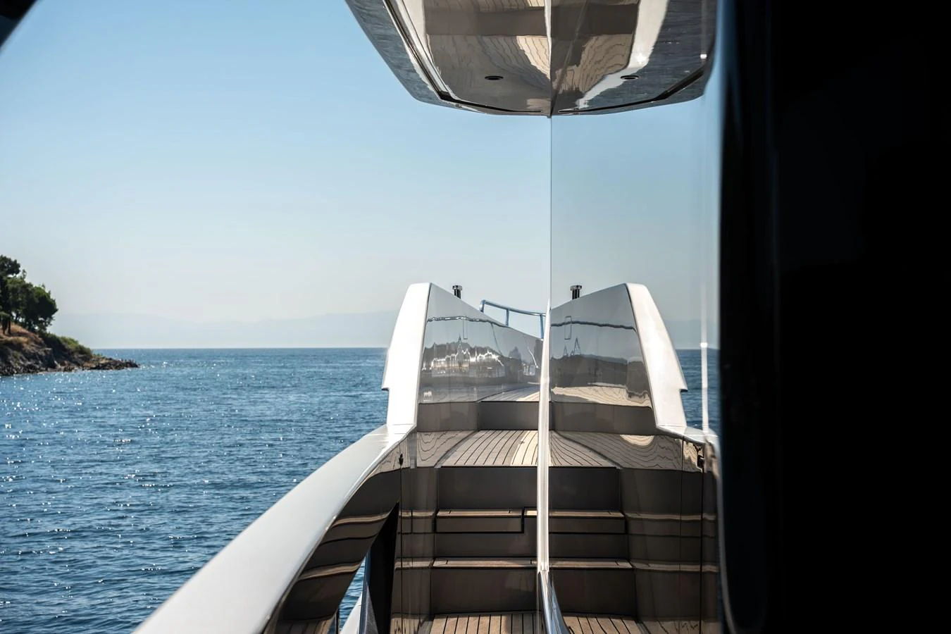 A sleek yacht is reflected in its own polished surfaces while cruising on calm waters. aboard CREA Yacht for Sale