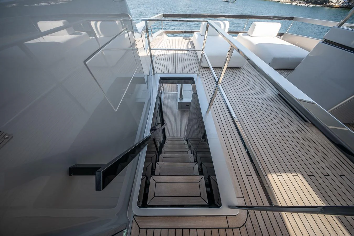 The flybridge features a sleek staircase leading down to the lower deck, with ample seating and stunning views of the water. aboard CREA Yacht for Sale