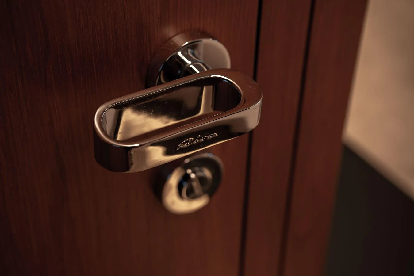 A close-up of a polished chrome door handle on a wooden surface. aboard CREA Yacht for Sale
