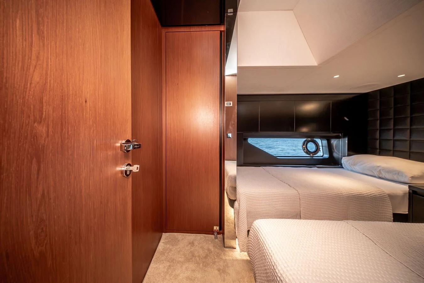 The stateroom features twin beds with a modern, minimalist design and warm wood accents. aboard CREA Yacht for Sale