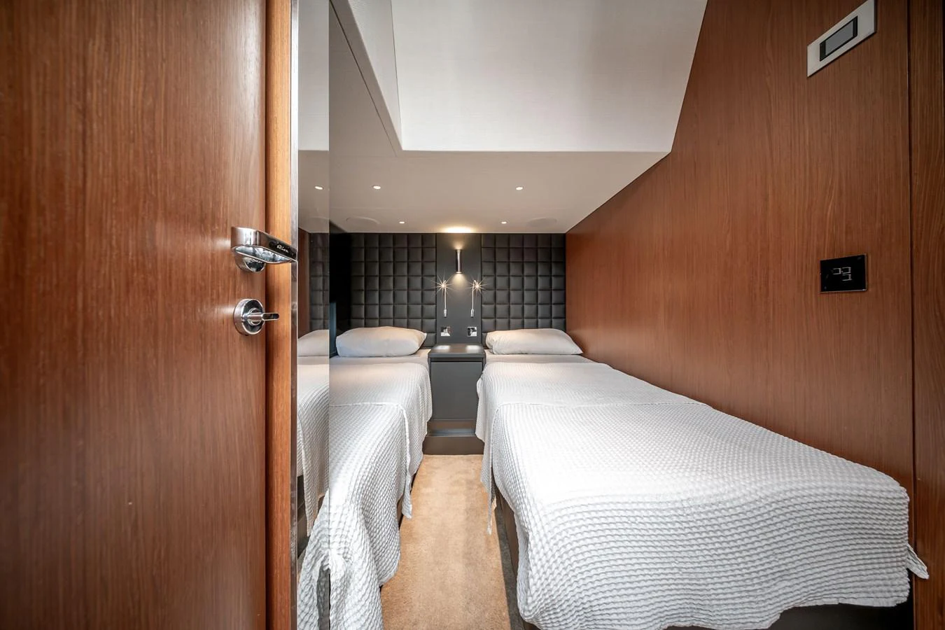 The twin cabin offers a cozy and modern sleeping arrangement with two single beds and elegant wood paneling. aboard CREA Yacht for Sale