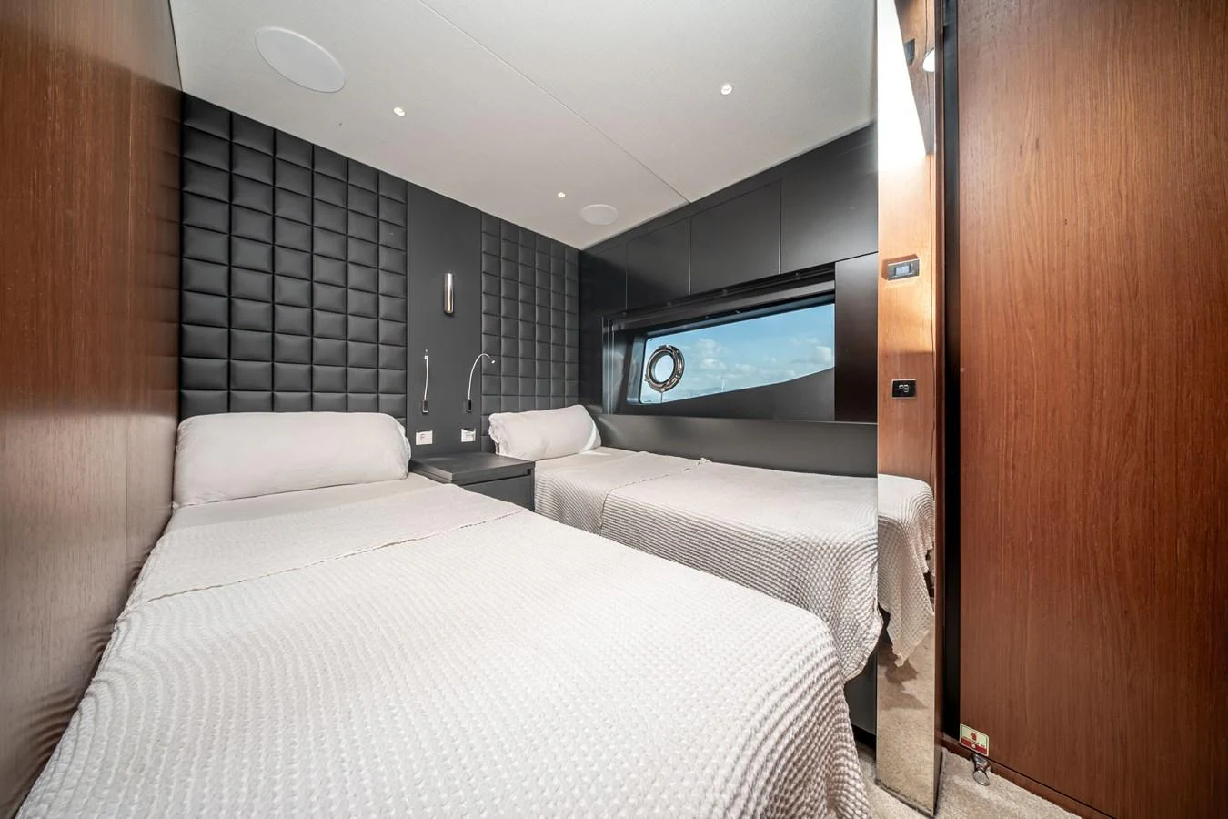 The guest stateroom features twin beds with a modern, sleek design and a large window for natural light. aboard CREA Yacht for Sale