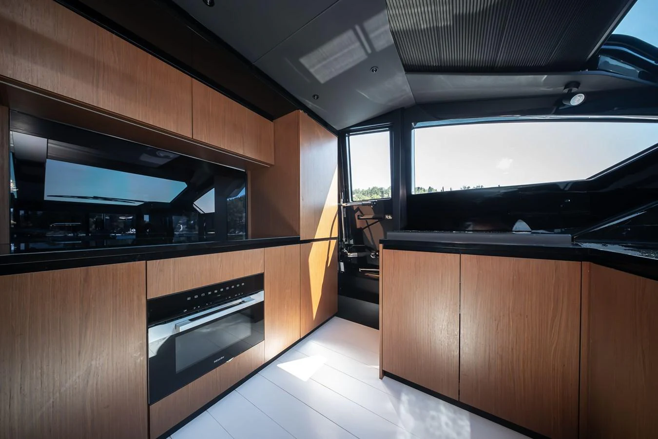 The yacht's galley features sleek wooden cabinetry and modern appliances, bathed in natural light. aboard CREA Yacht for Sale