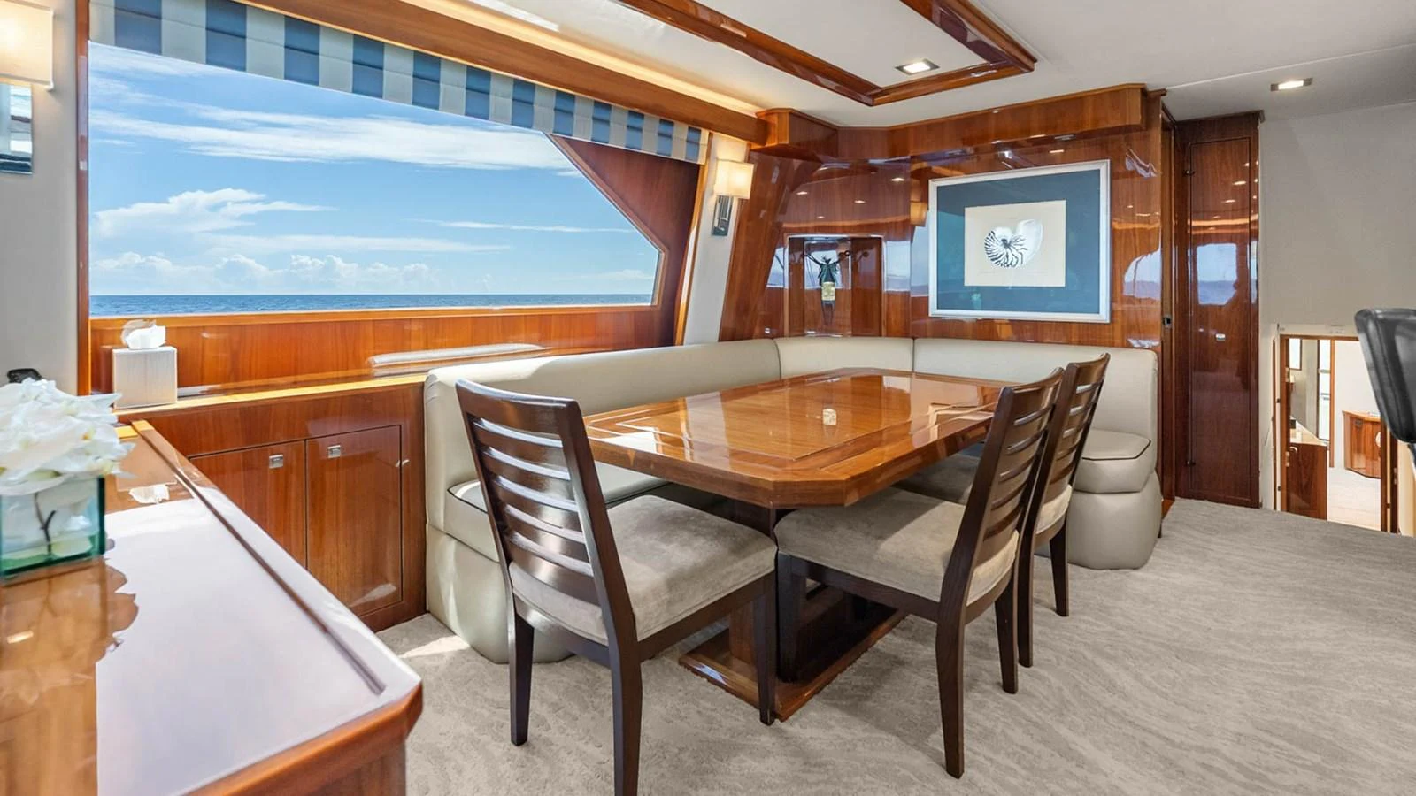 The yacht's dining area features a polished wooden table surrounded by comfortable seating, with large windows offering stunning ocean views. aboard DOUBLE BARREL Yacht for Sale