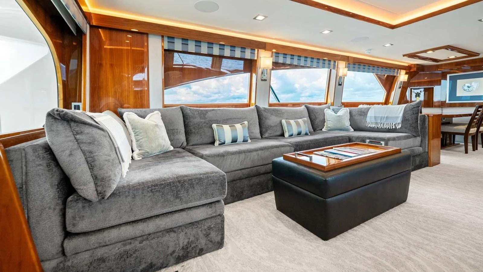 The salon features a spacious and luxurious seating area with plush gray sofas and large windows offering stunning views. aboard DOUBLE BARREL Yacht for Sale