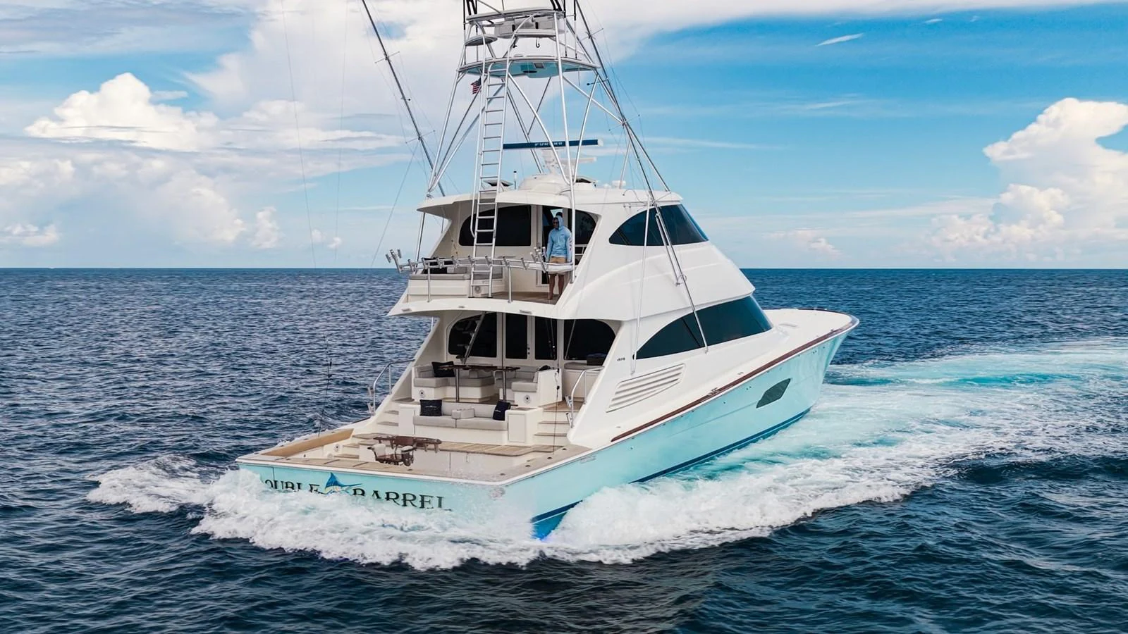 A sleek yacht cruises through the open sea under a clear blue sky. aboard DOUBLE BARREL Yacht for Sale