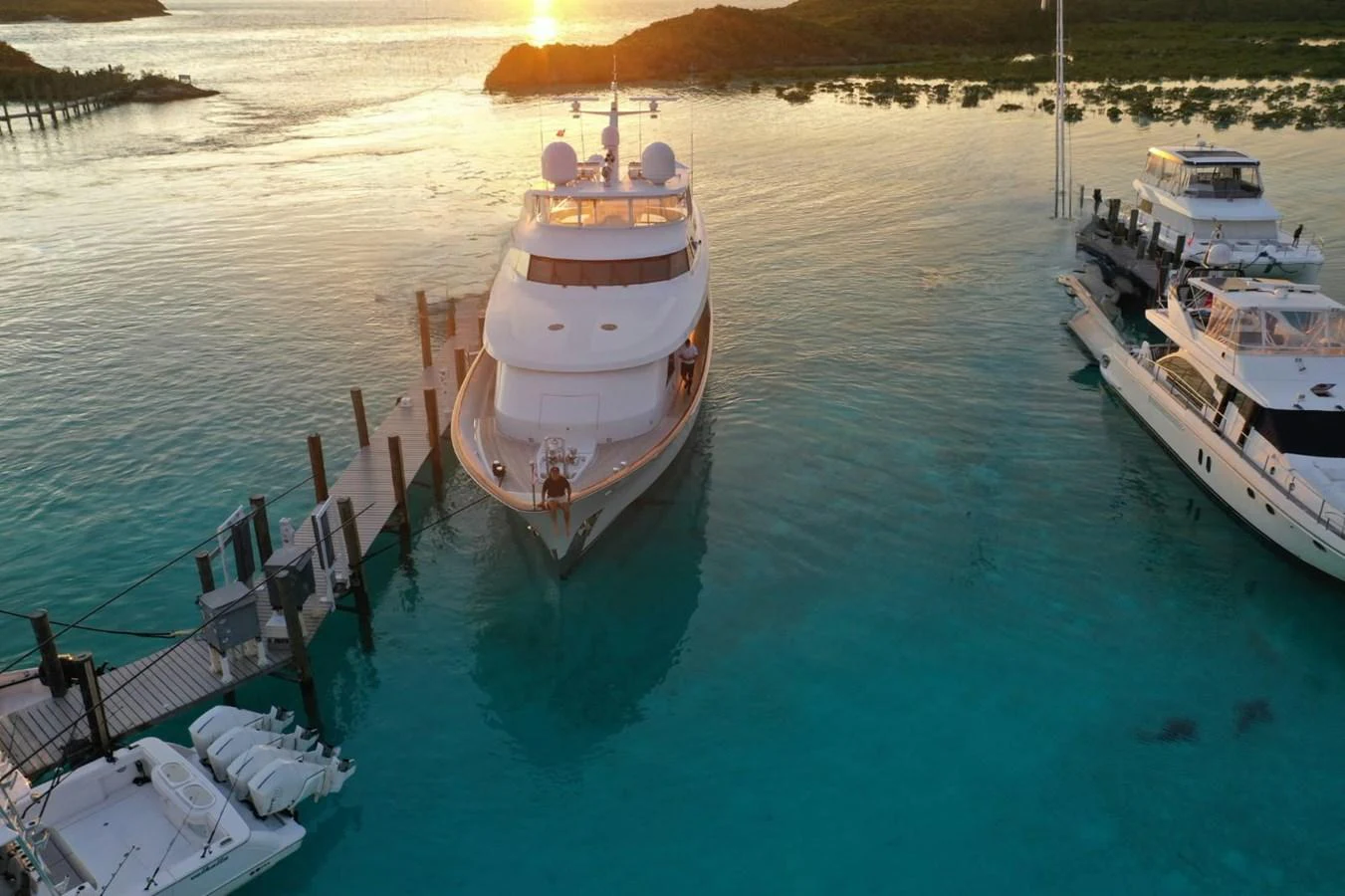 A luxurious yacht is docked in a serene marina at sunset, surrounded by calm turquoise waters. aboard UKARA Yacht for Sale