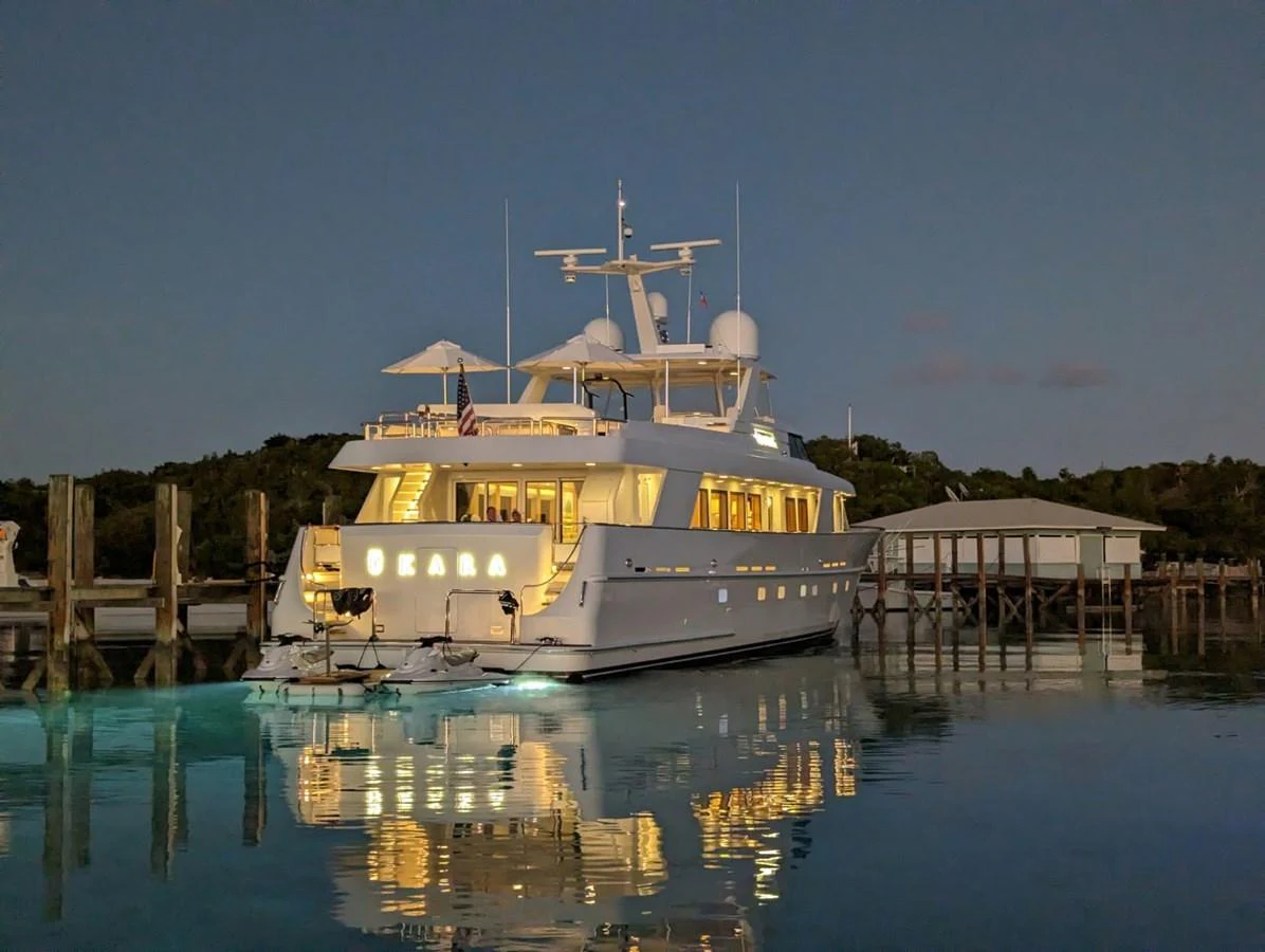 A luxurious yacht is beautifully illuminated at dusk, reflecting on calm waters near a dock. aboard UKARA Yacht for Sale