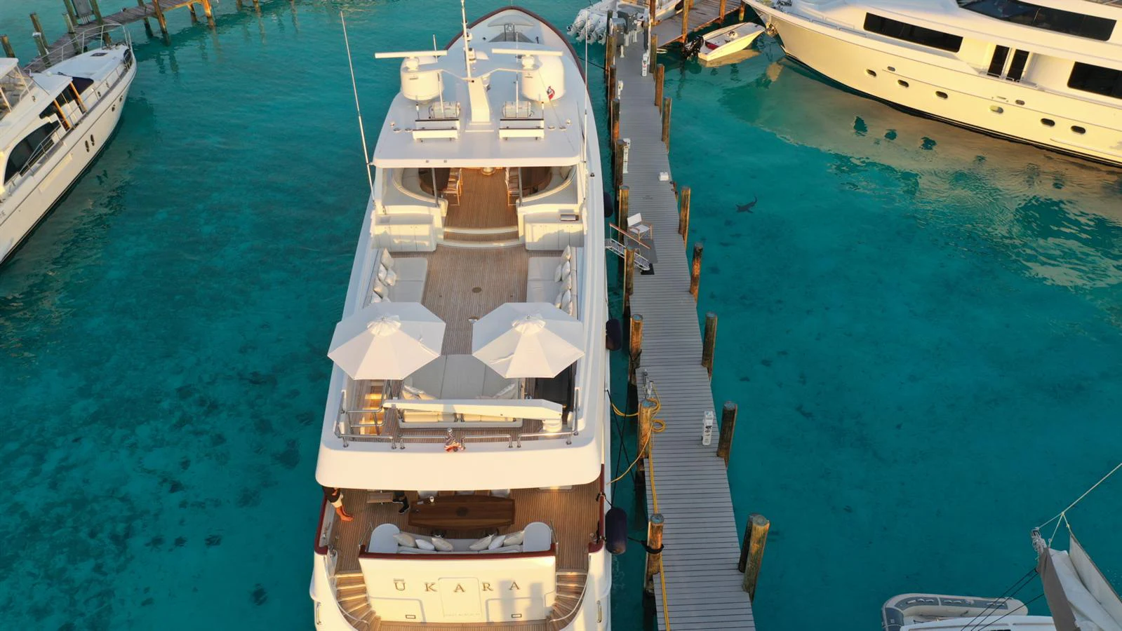 A luxurious yacht is docked in a serene marina with clear turquoise waters. aboard UKARA Yacht for Sale