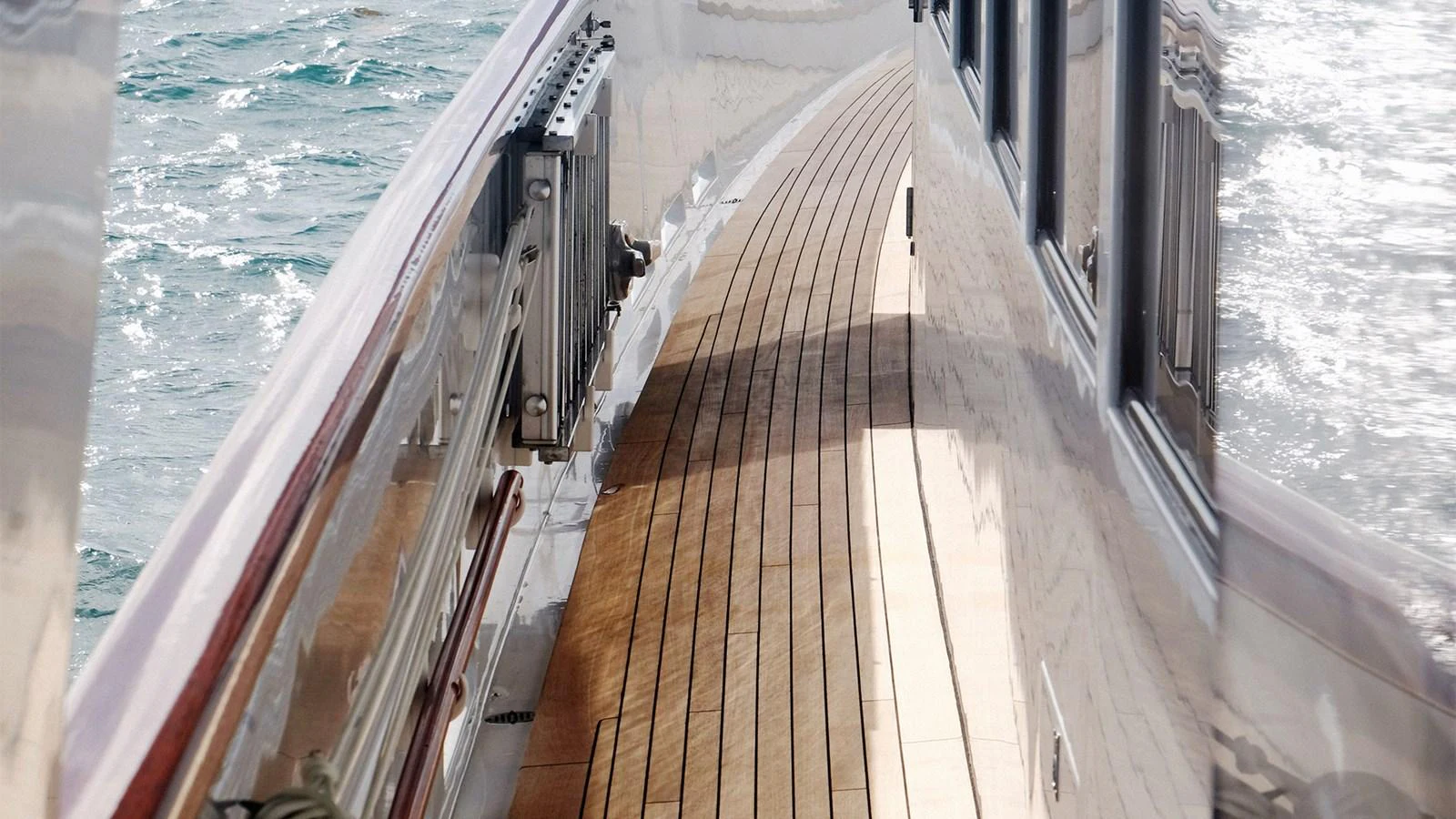 The side deck features elegant teak flooring and polished railings, offering a serene view of the surrounding waters. aboard UKARA Yacht for Sale