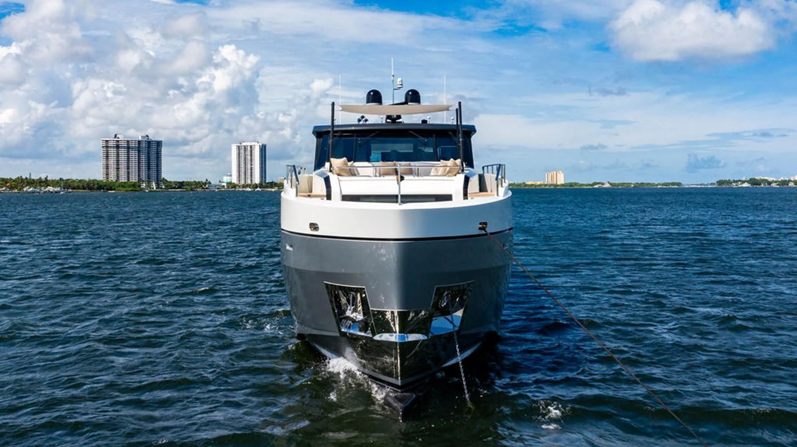 A modern yacht cruising on calm waters with a cityscape in the background. aboard M/Y 12 Yacht for Sale