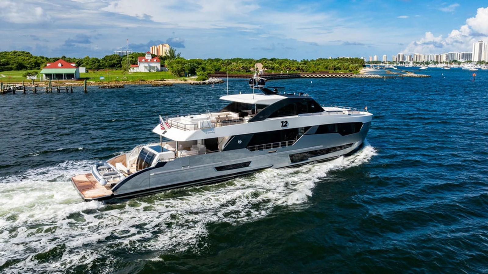 A sleek and modern yacht cruises through the water near a coastal city. aboard M/Y 12 Yacht for Sale