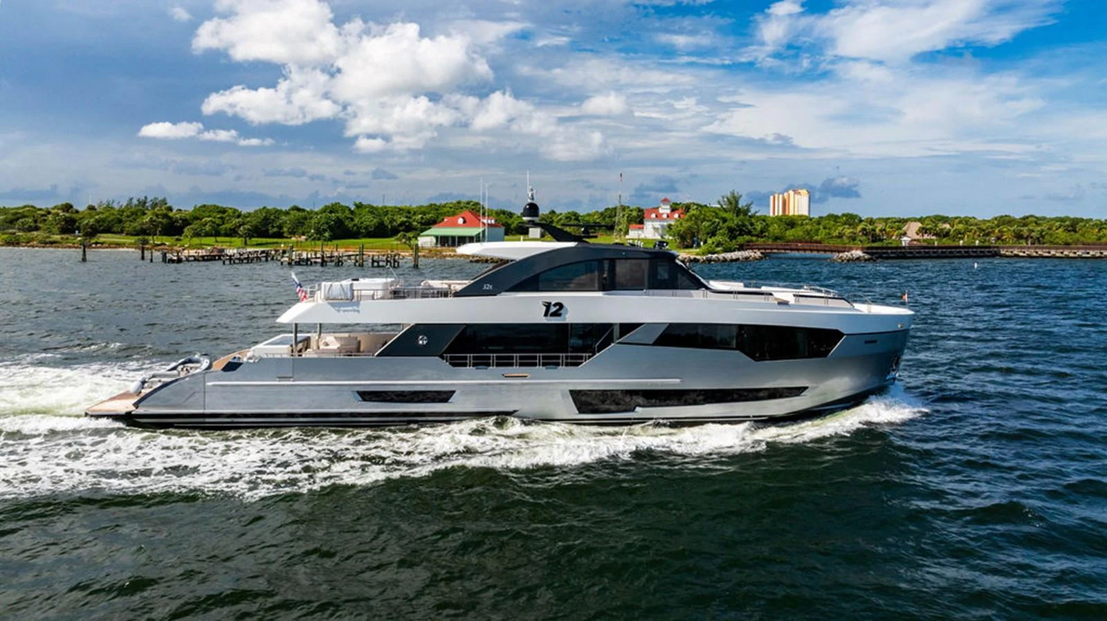 A sleek and modern yacht cruises through calm waters with a scenic shoreline in the background. aboard M/Y 12 Yacht for Sale