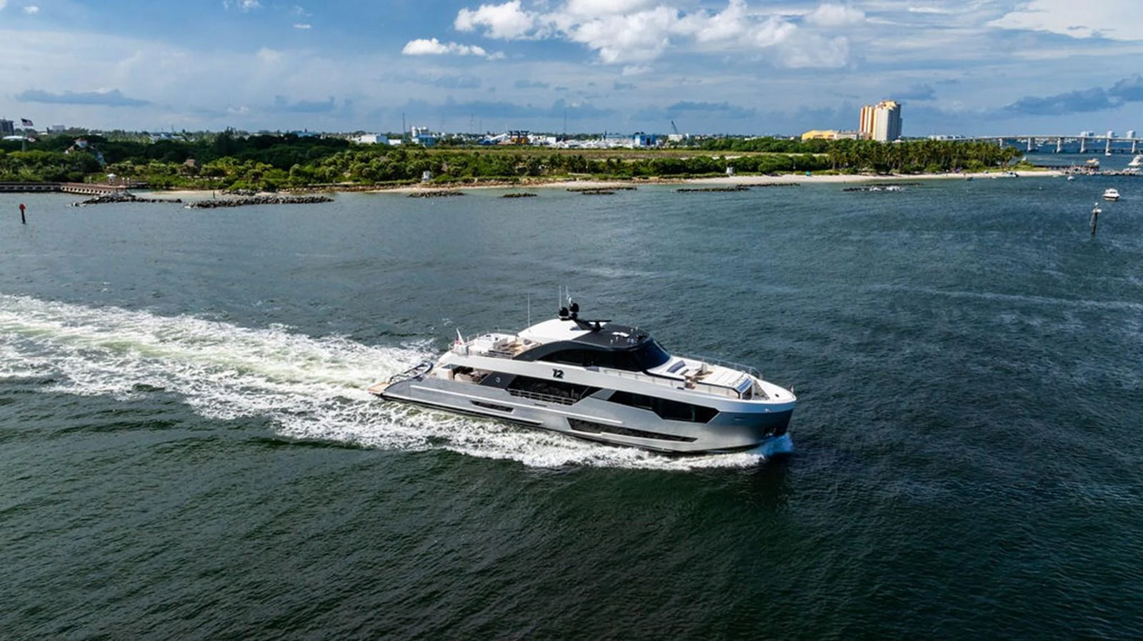 A sleek yacht cruises through calm waters with a scenic coastline in the background. aboard M/Y 12 Yacht for Sale