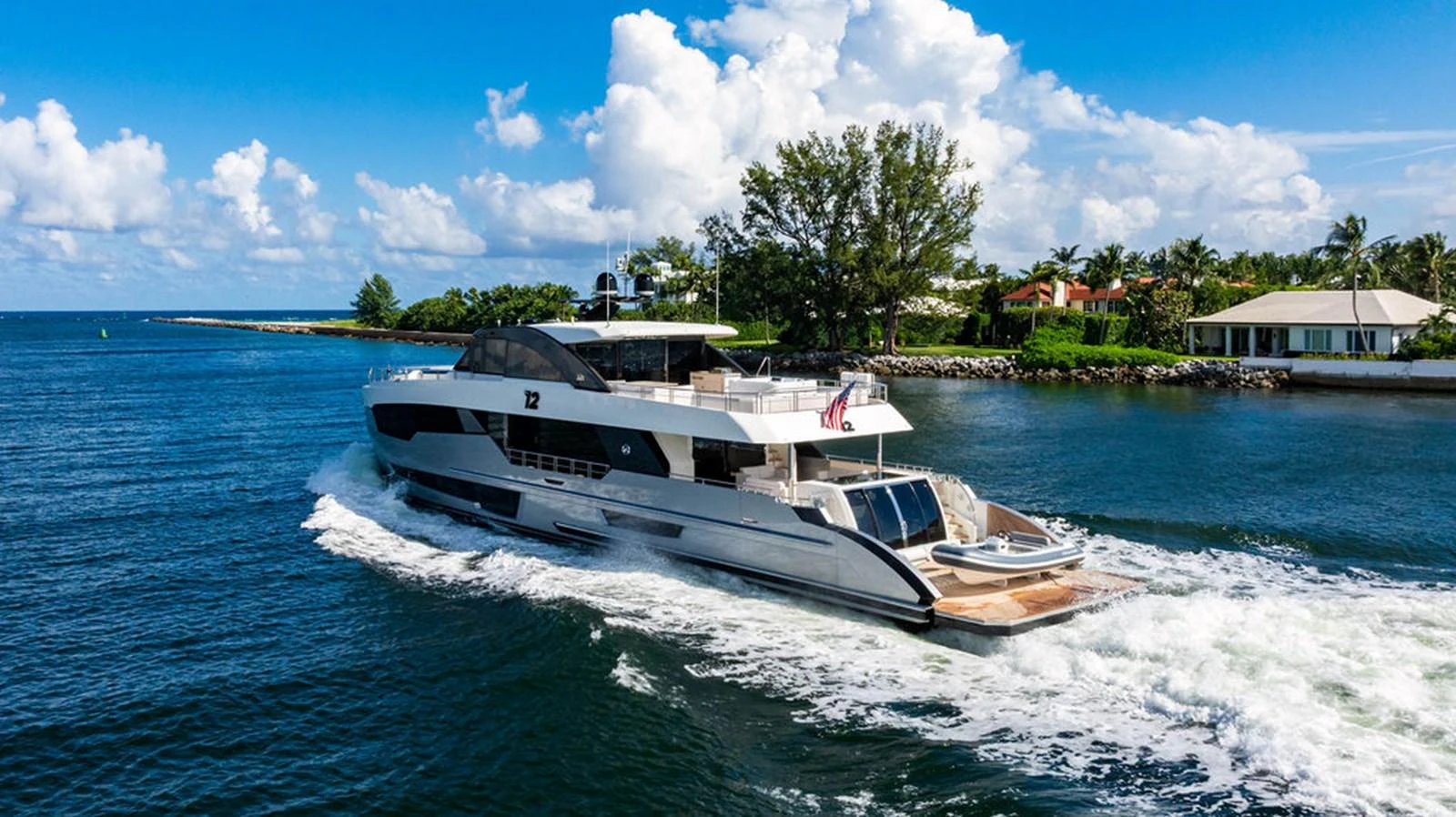 A sleek and modern yacht cruising through a serene waterway under a bright blue sky. aboard M/Y 12 Yacht for Sale