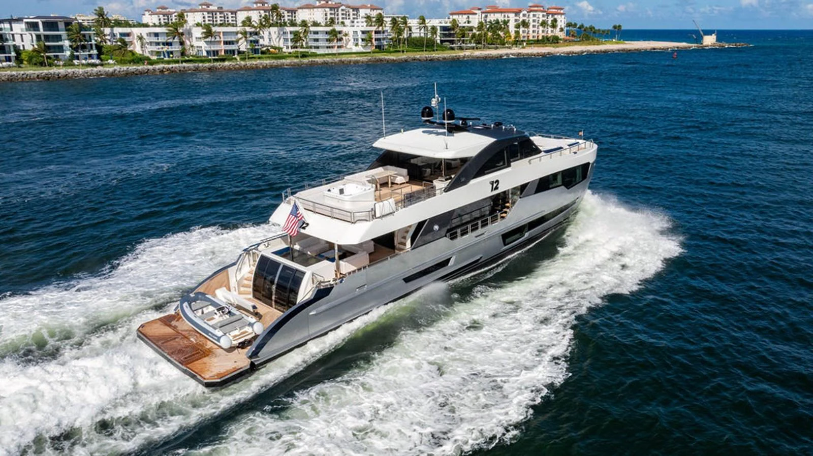 A sleek and modern yacht cruises through the water near a coastal city. aboard M/Y 12 Yacht for Sale