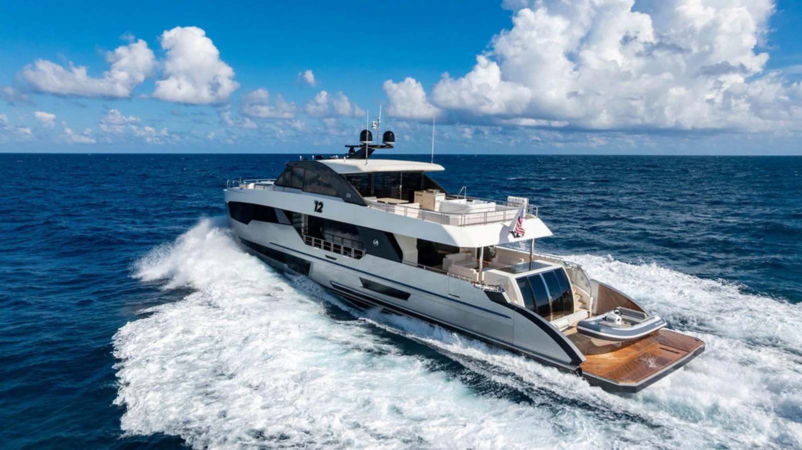 A sleek and modern yacht cruises through the open sea under a bright blue sky. aboard M/Y 12 Yacht for Sale