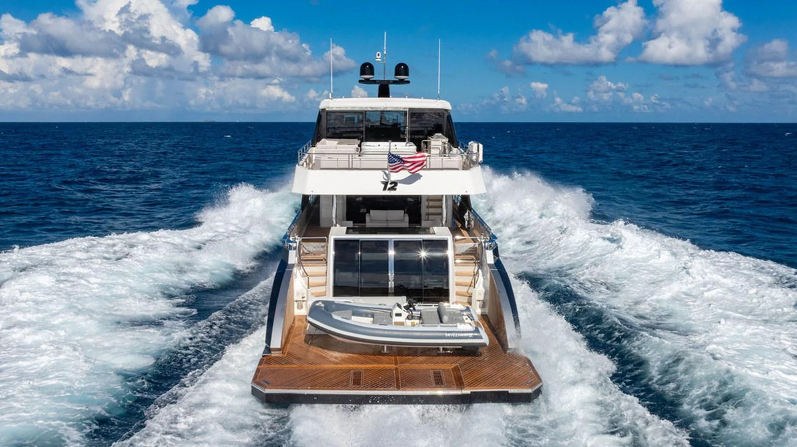 A luxurious yacht cruises through the open sea, leaving a trail of white waves behind. aboard M/Y 12 Yacht for Sale