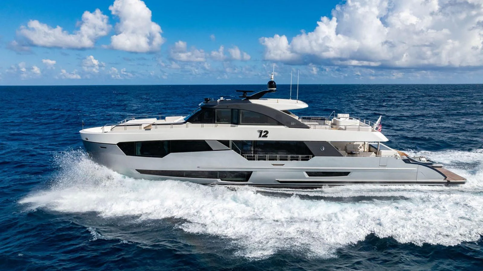 A sleek and modern yacht cruises swiftly through the open ocean under a bright blue sky. aboard M/Y 12 Yacht for Sale