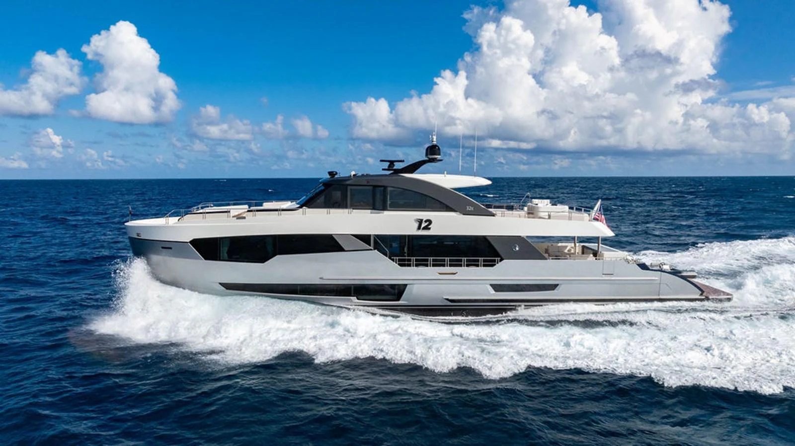 A sleek and modern yacht cruises swiftly through the open sea under a bright blue sky. aboard M/Y 12 Yacht for Sale
