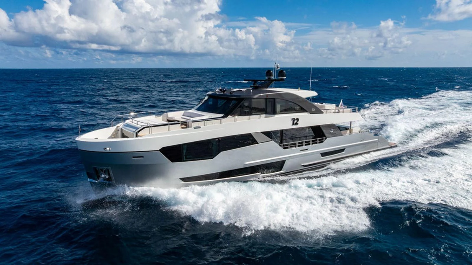 A sleek and modern yacht cruising through the open ocean under a bright blue sky. aboard M/Y 12 Yacht for Sale