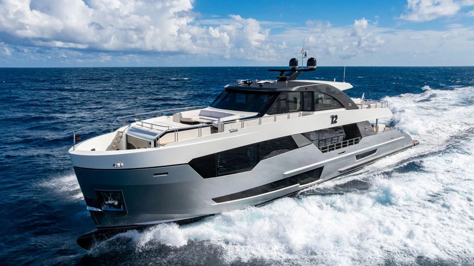 A sleek and modern yacht cruises through the open sea under a bright blue sky. aboard M/Y 12 Yacht for Sale
