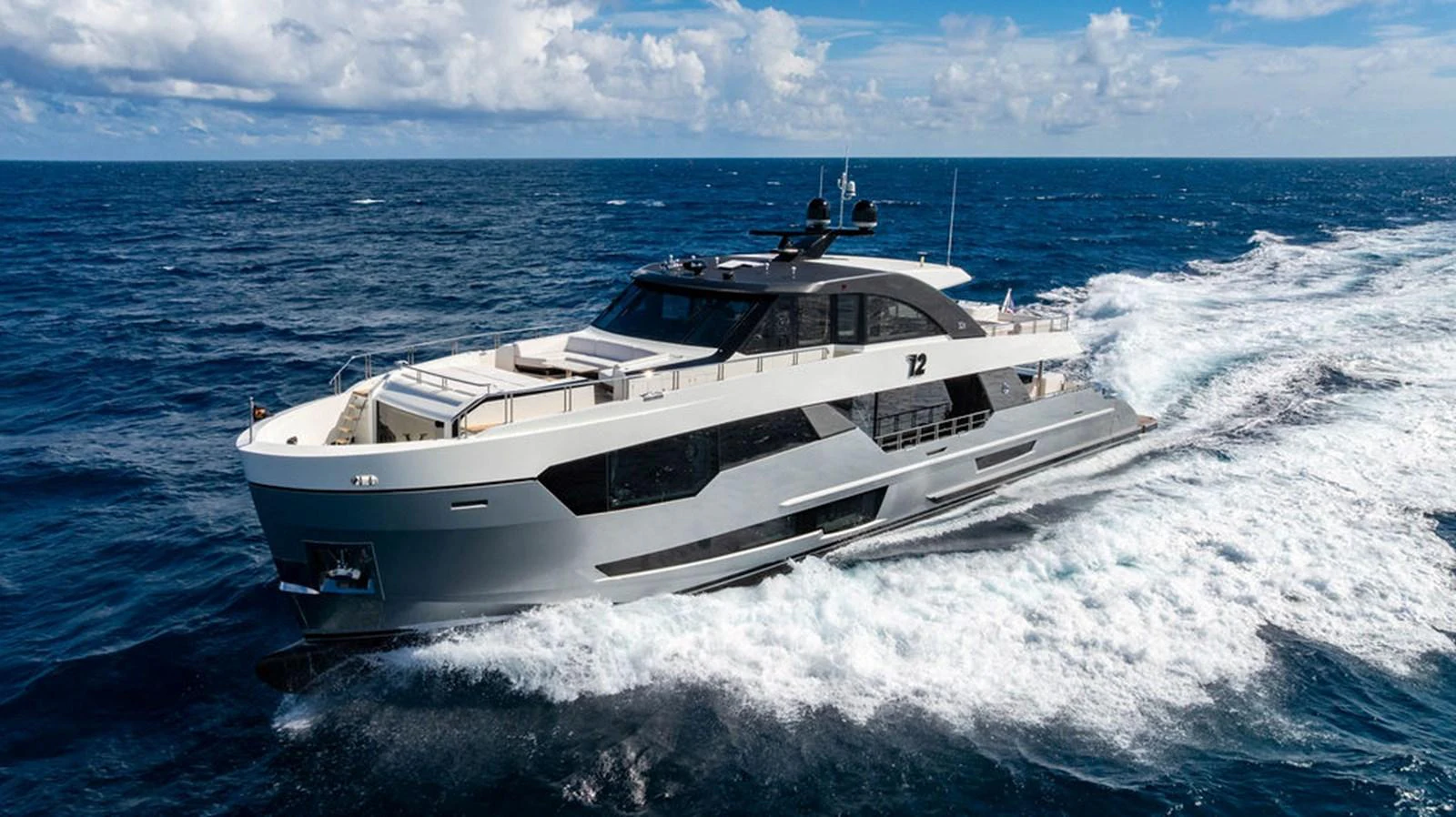 A sleek and modern yacht cruises through the open ocean under a bright blue sky. aboard M/Y 12 Yacht for Sale