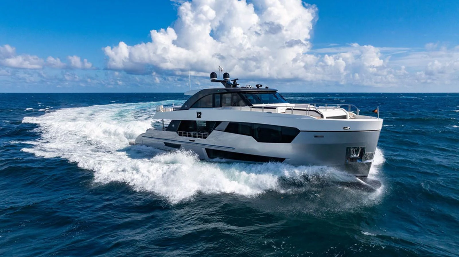 A sleek and modern yacht cruises swiftly through the open sea under a bright blue sky. aboard M/Y 12 Yacht for Sale