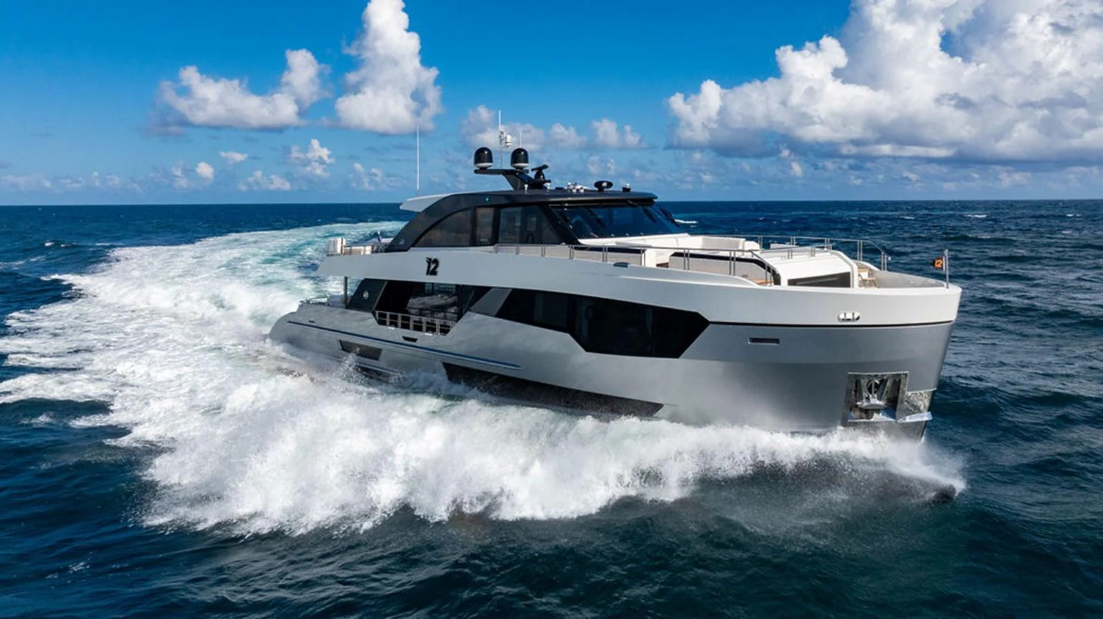 A sleek and modern yacht cruises swiftly through the open sea under a bright sky. aboard M/Y 12 Yacht for Sale