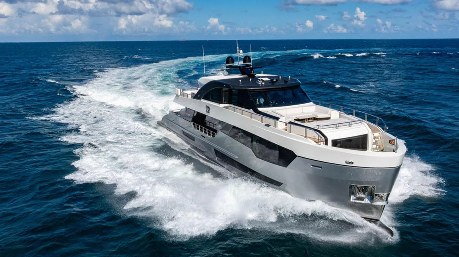 A sleek and modern yacht cruises swiftly through the open ocean under a bright blue sky. aboard M/Y 12 Yacht for Sale